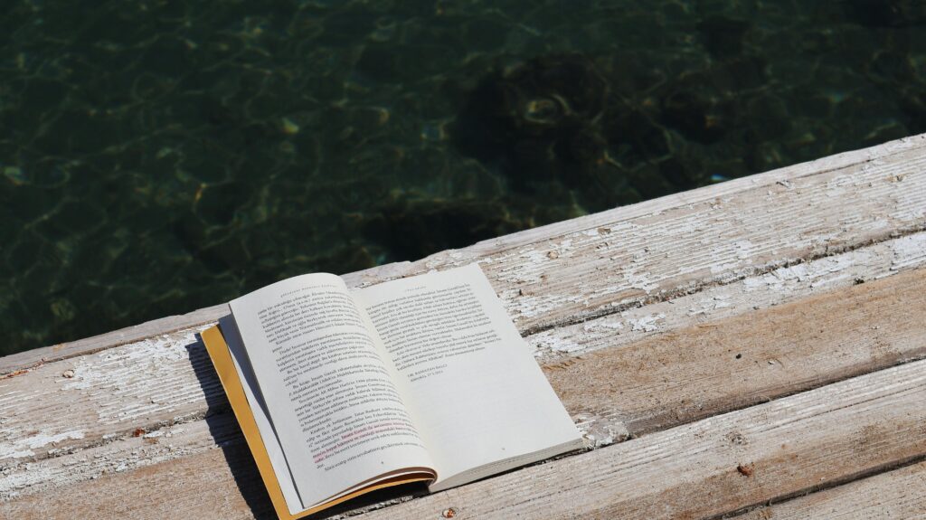 Libro abierto sobre tabla de madera al lado del agua