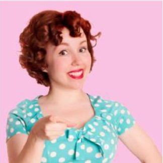 Una mujer pelirroja con un traje azul con topos blancos de estilo vintage