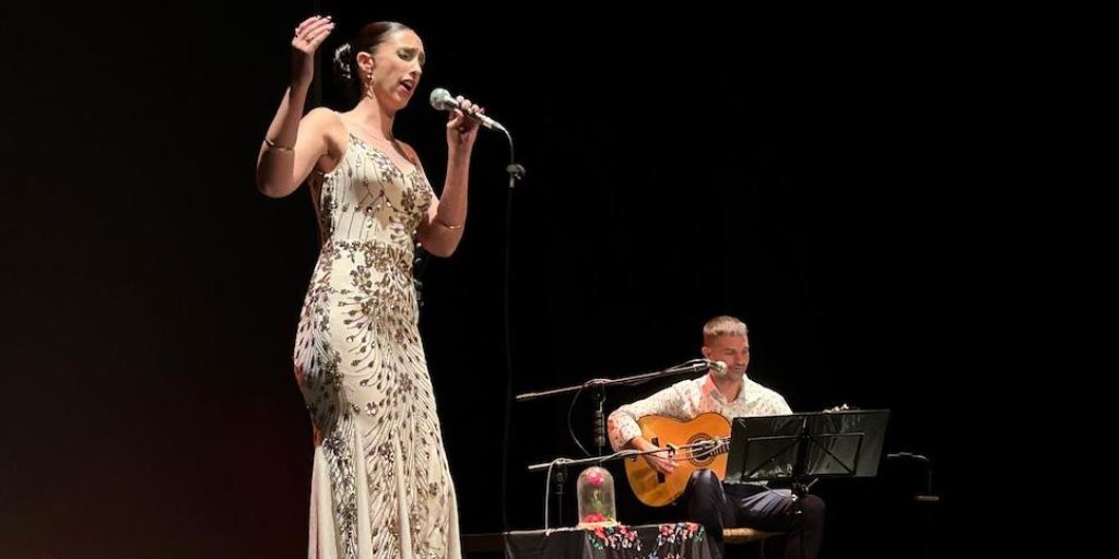 Una mujer cantando con un vestido y un hombre sentado tocando la guitarra