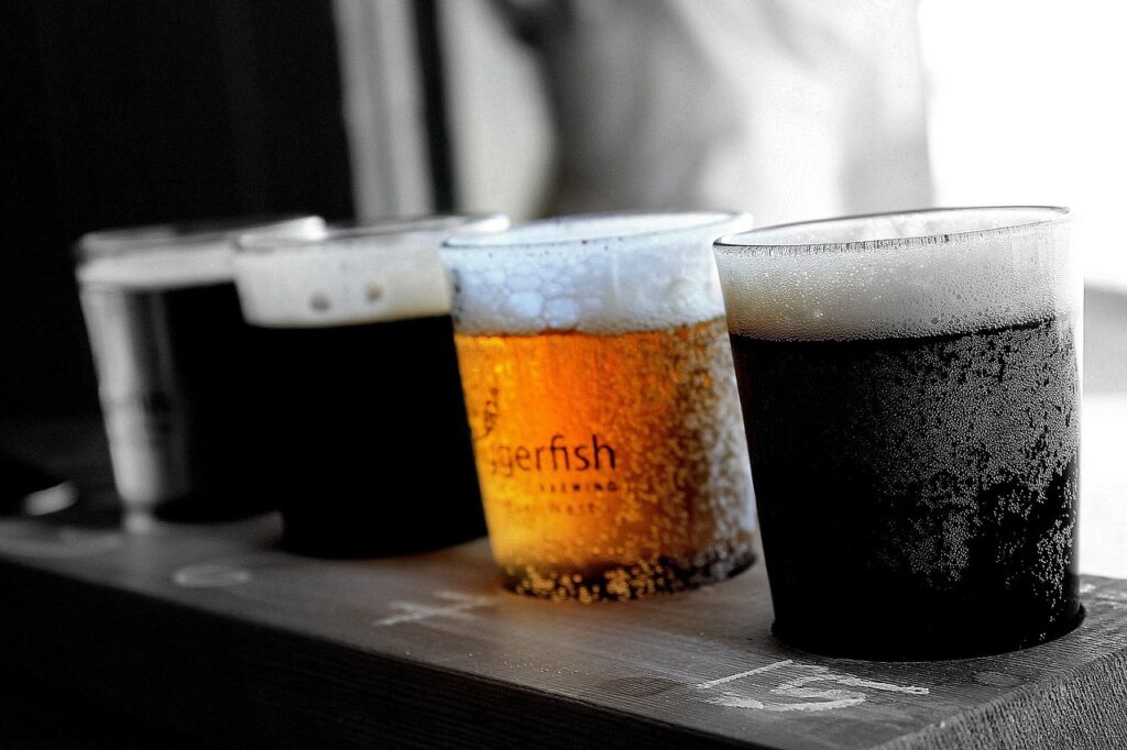 cuatro vasos de cervezas de diferente tipo sobre una barra de madera