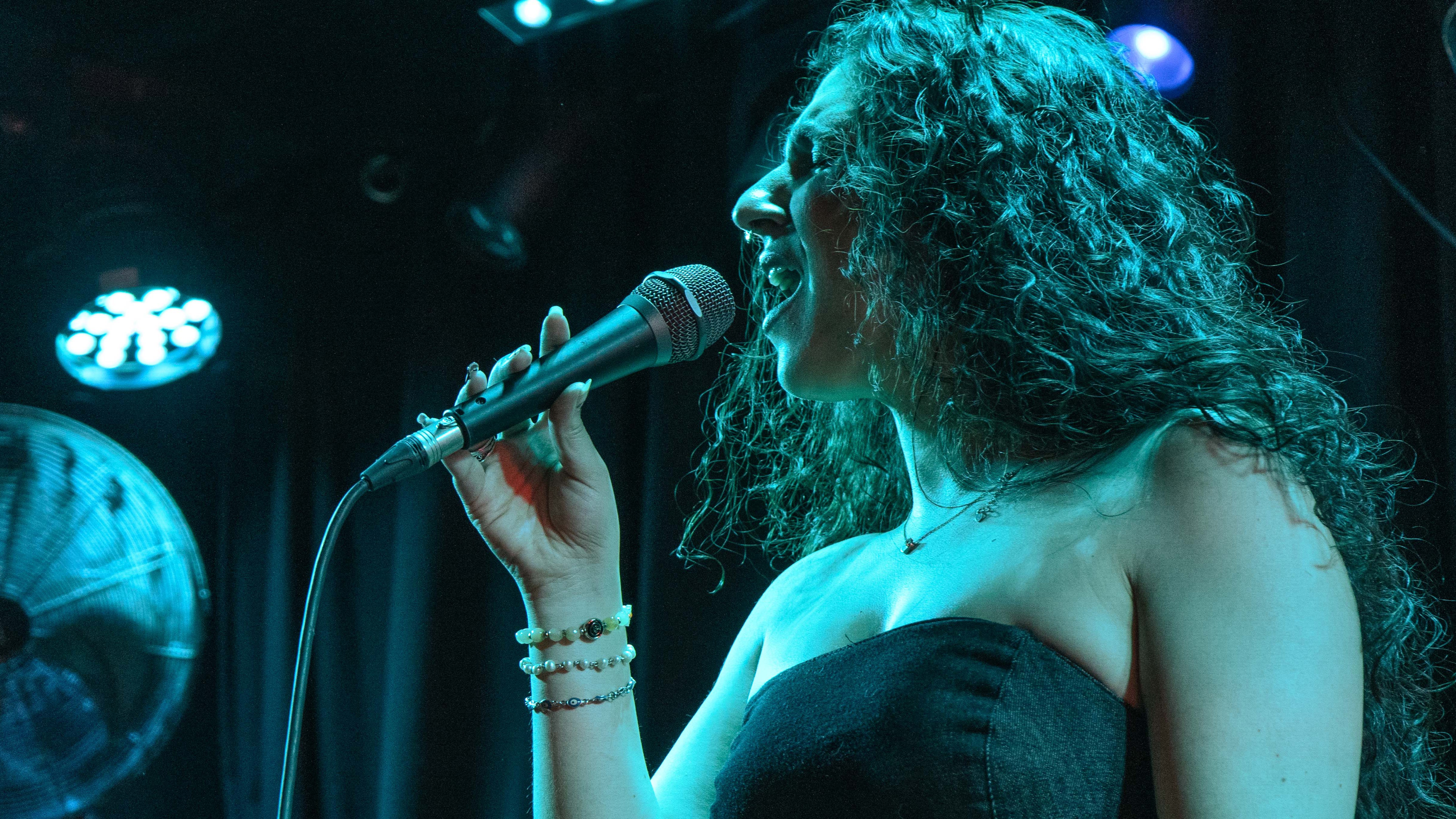 Foto promocional de Yael Levi donde se ve a la artista de perfil cantando, enfocada con tonos azulados verdosos