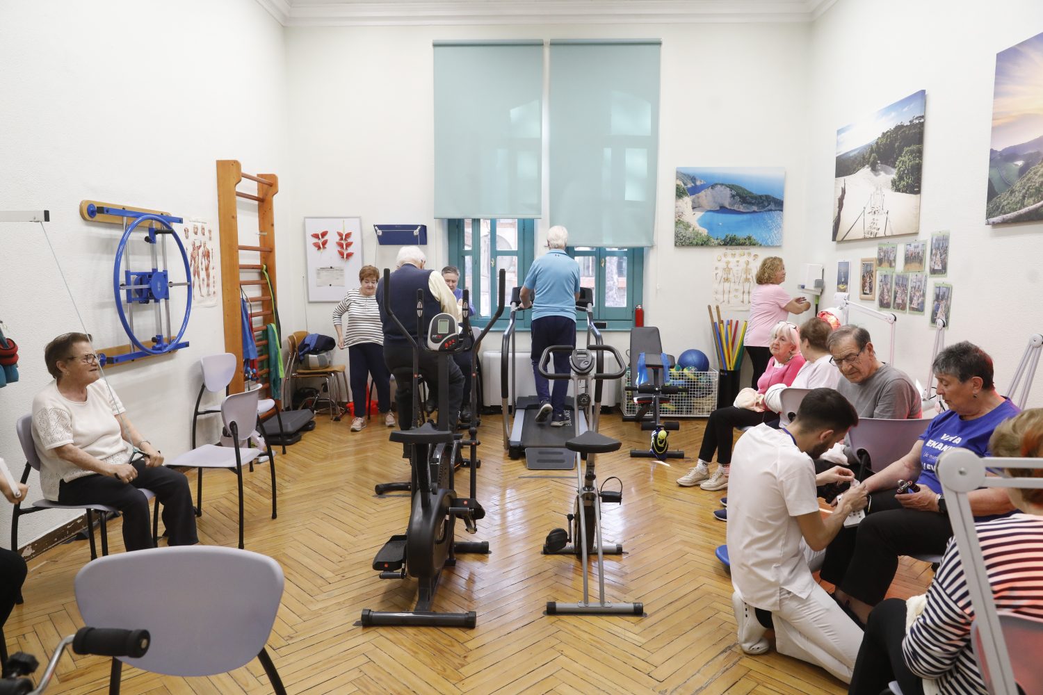 Personas mayores realizando ejercicios en una sala de rehabilitación con supervisión profesional.